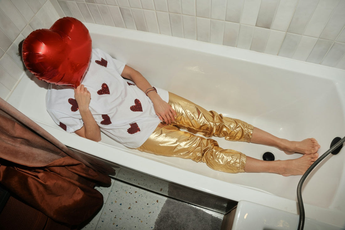 Person in bathtub with heart ballon over face.