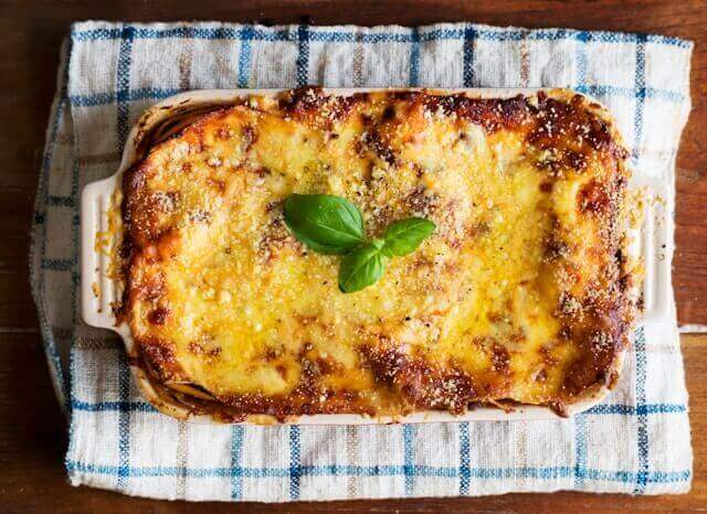 Lasagna on a blue and white checkered towel on a kitchen countertop.