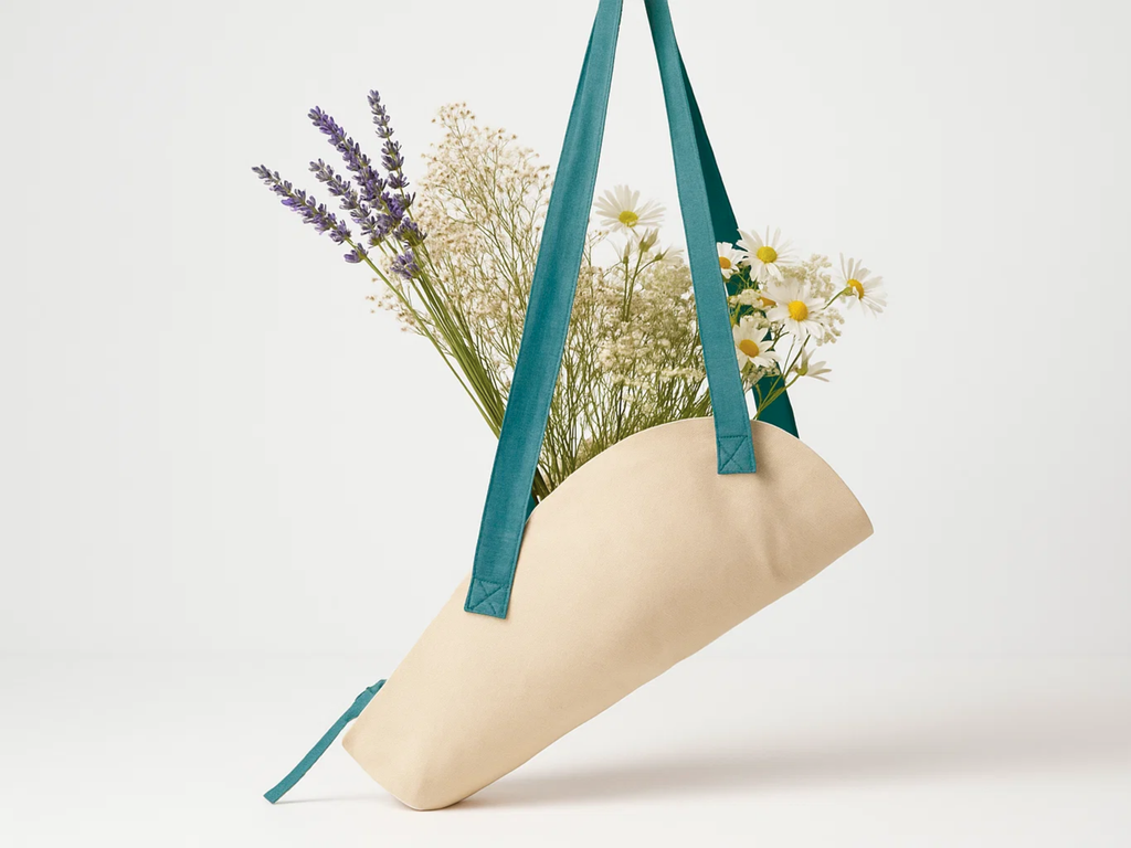 Beige cylindrical vase with teal handles holding flowers on a white background