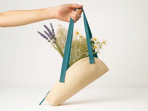 Beige bag with teal handles holding flowers on a white background