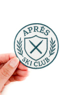 Round patch with 'Apres Ski Club' text held by a hand on a white background