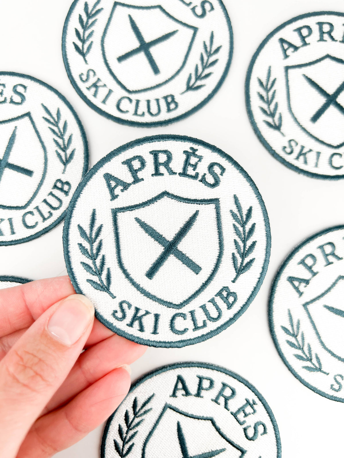 Stickers with 'APRèS SKI CLUB' design held by a hand on a light background