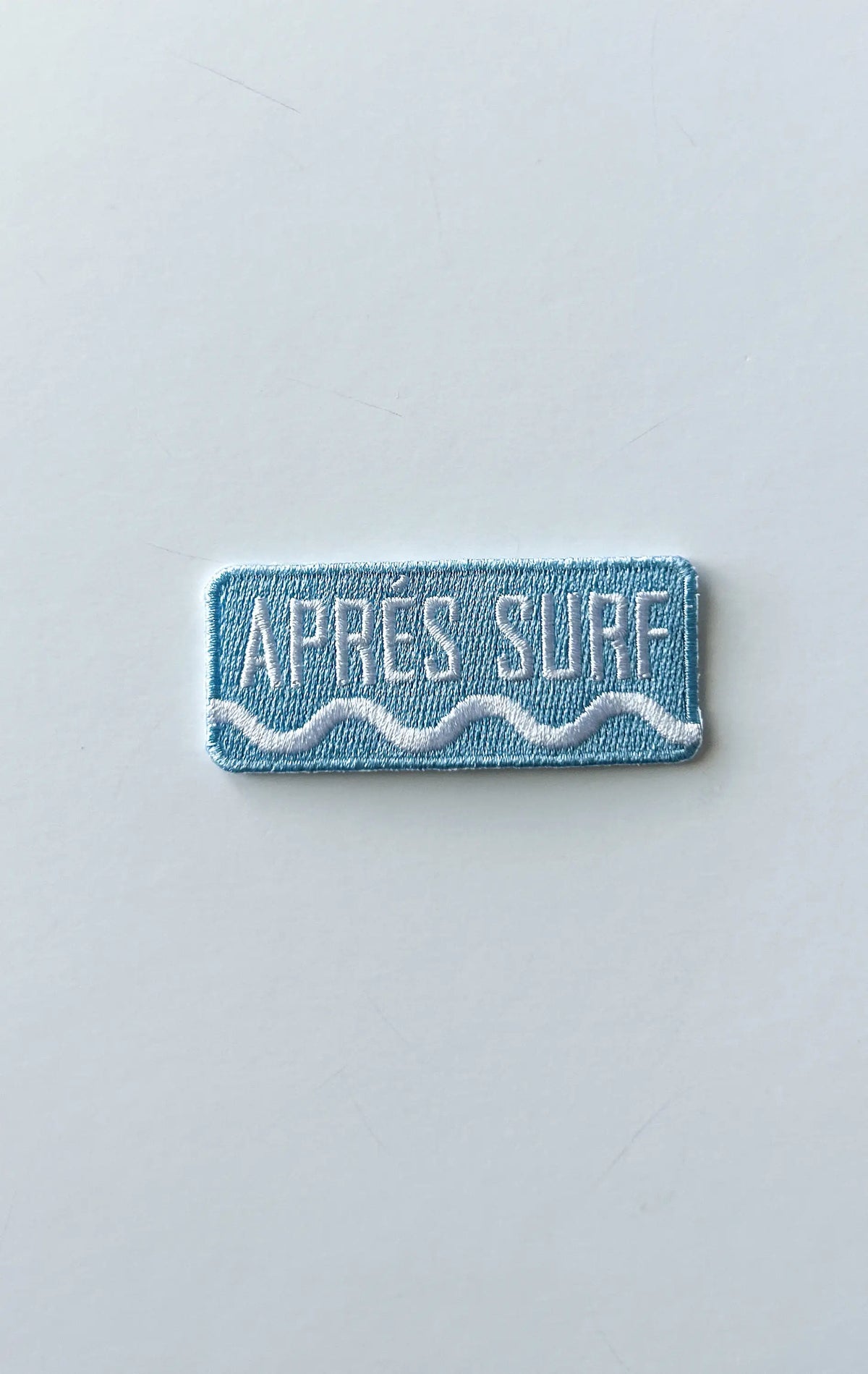 Rectangular patch with 'Apres Surf' text on a light gray background