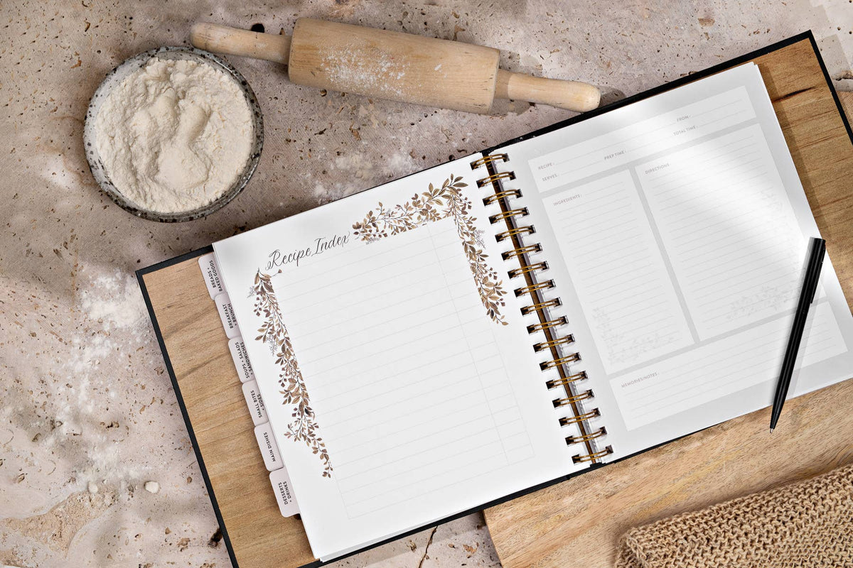 Open planner with decorative elements on a kitchen counter with flour and rolling pin.