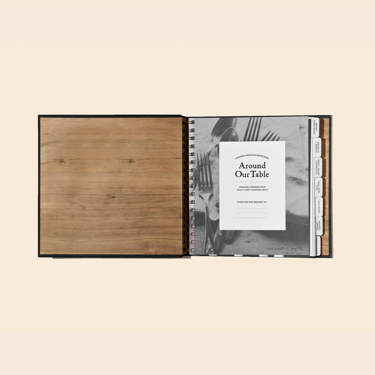 Open spiral-bound notebook with wooden cover and 'Around Our Table' branding on a beige background