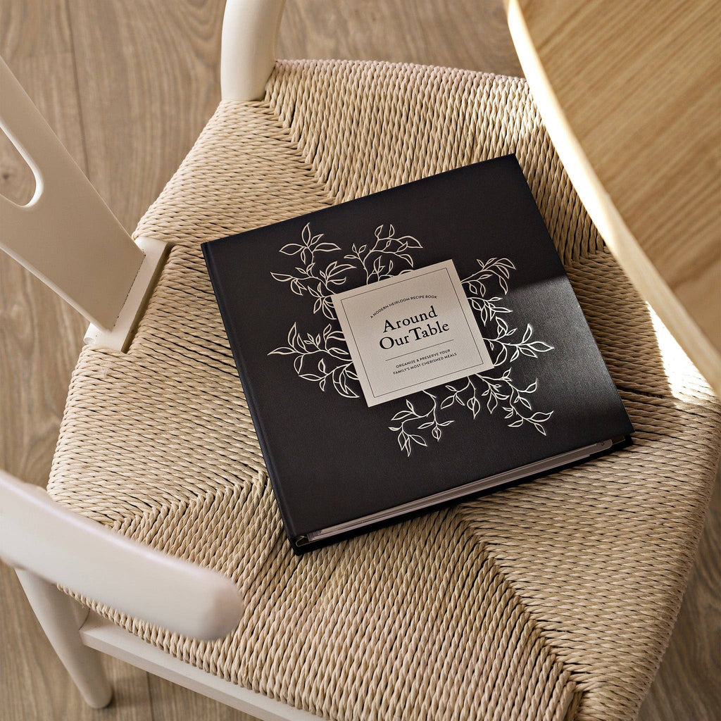 Black book with decorative cover on a wicker chair