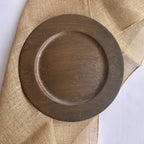 A round dark brown wooden tray with a raised rim, shown from above on a beige burlap fabric background.