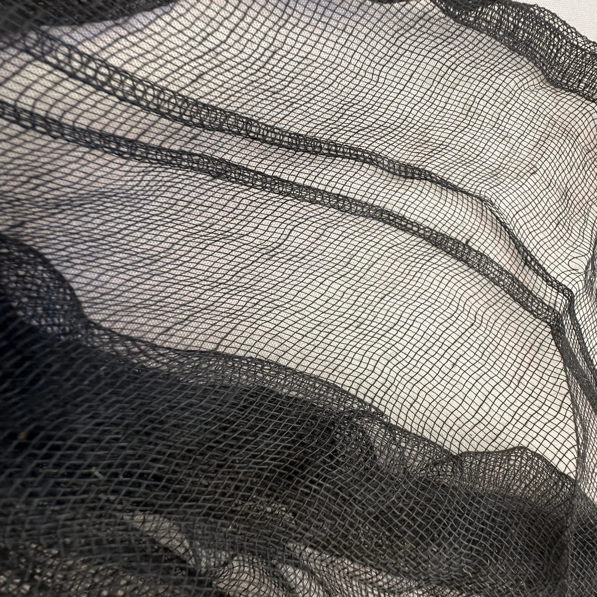 Black sheer mesh fabric with a fine grid pattern, draped to show its texture and transparency.