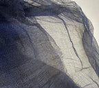 A close-up of sheer dark navy blue mesh fabric draped diagonally across the frame, showing its fine woven texture and semi-transparent quality.