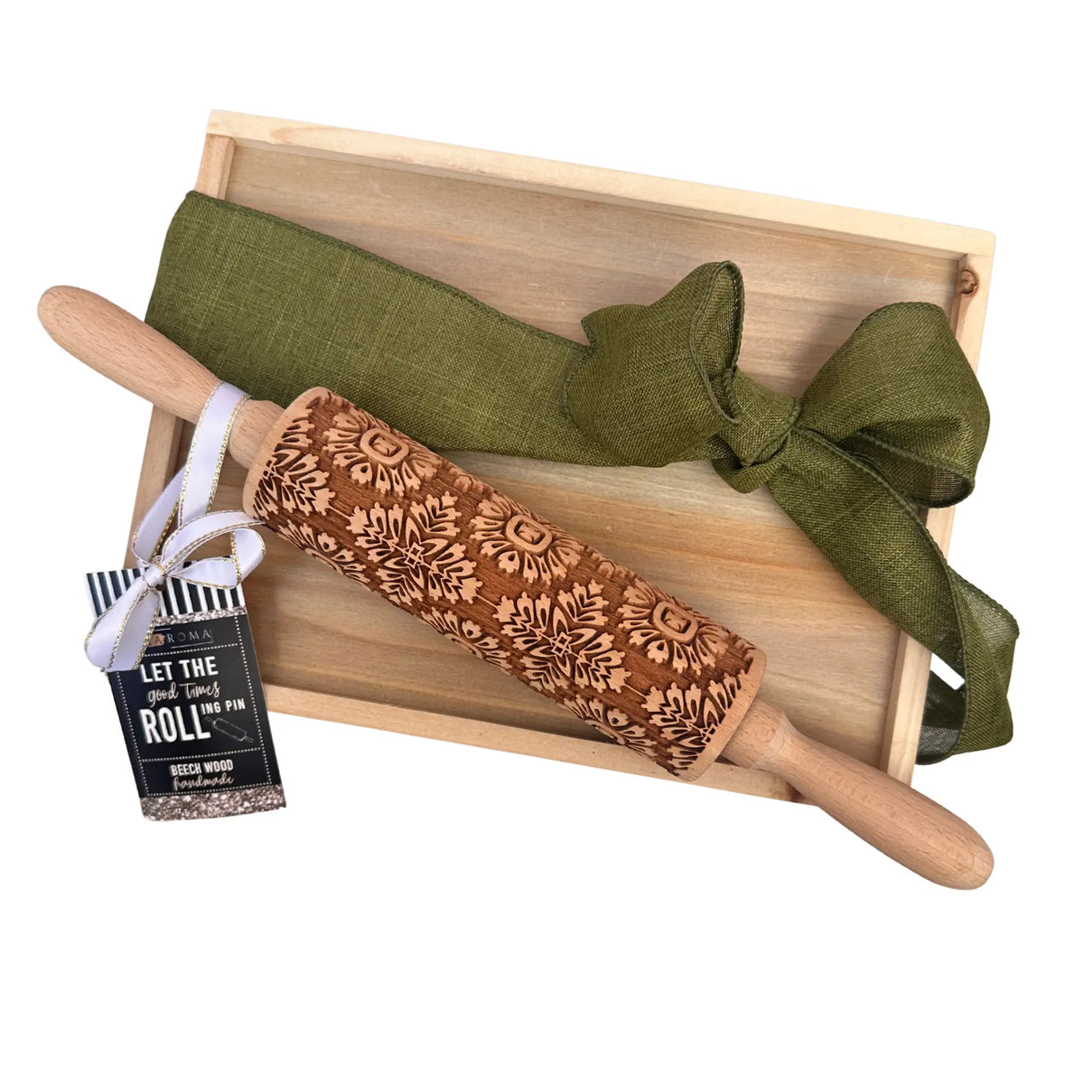 A wooden rolling pin with a floral laser-engraved pattern, presented on a light wood gift tray with an olive green ribbon and a hanging tag that reads 'LET THE good times ROLL IN'.