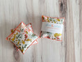 Two floral lavender sachets on a wooden surface with 'dot & amy' packaging.
