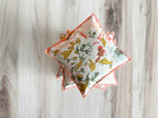 Decorative square pillows with floral patterns on a wooden surface