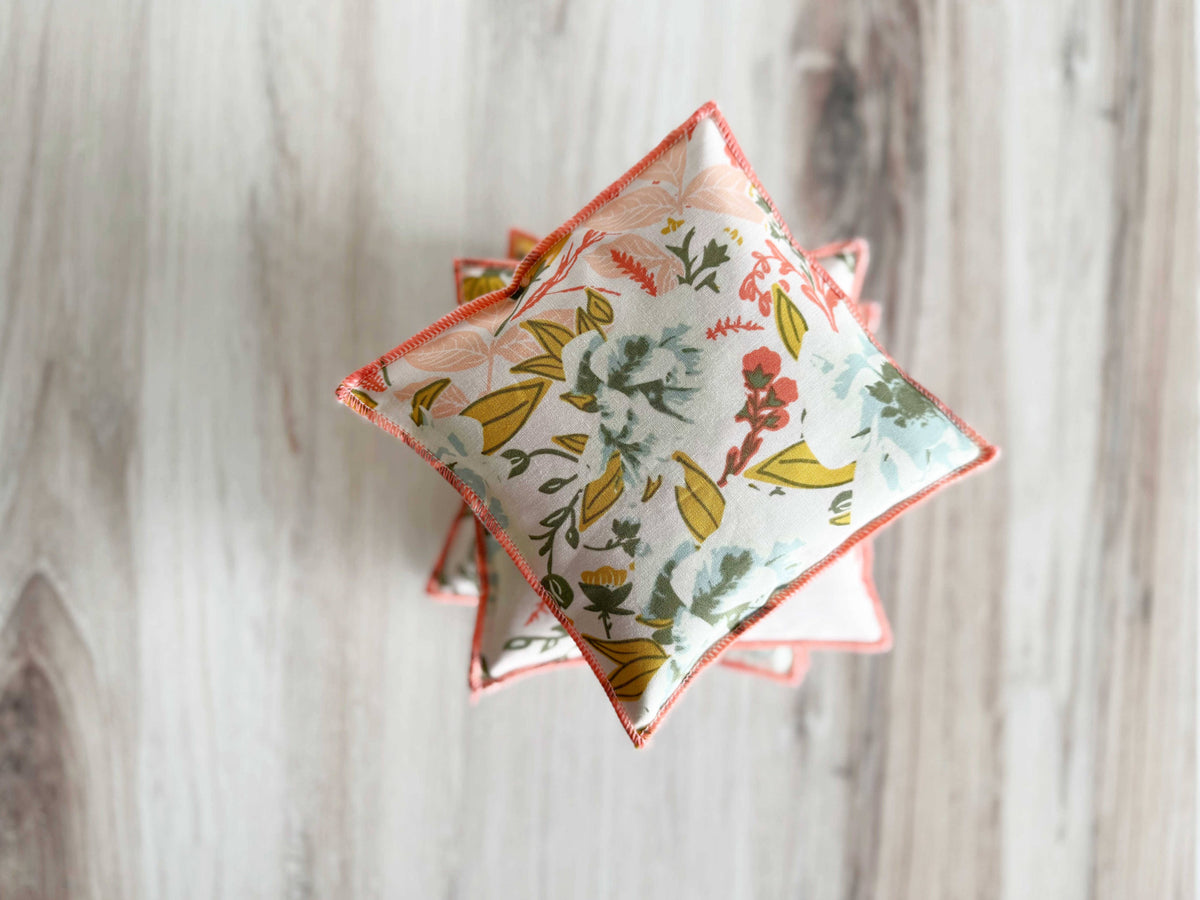 Decorative square pillows with floral patterns on a wooden surface