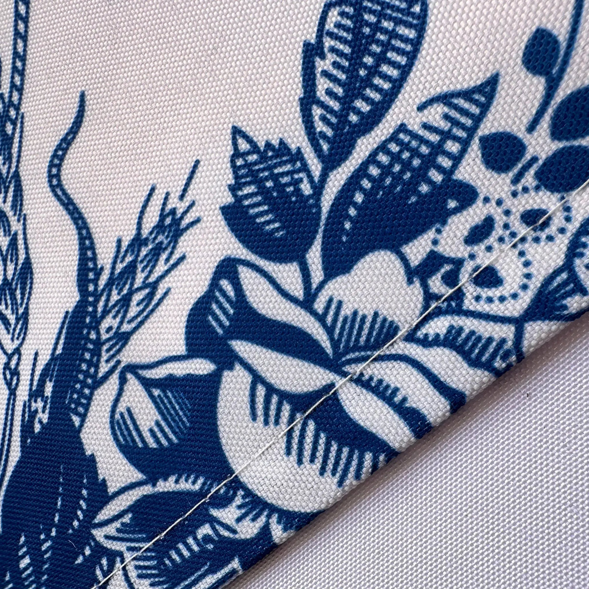 Close-up of a folded textile corner showing a navy blue floral and botanical print on a white fabric background.