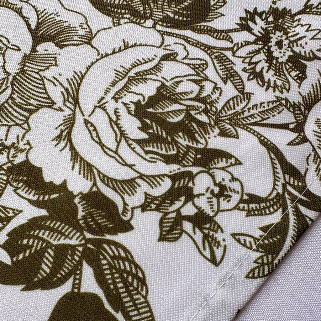 A close-up of a woven fabric with a dark olive-green floral toile pattern on a white background, showing the texture and a folded corner.