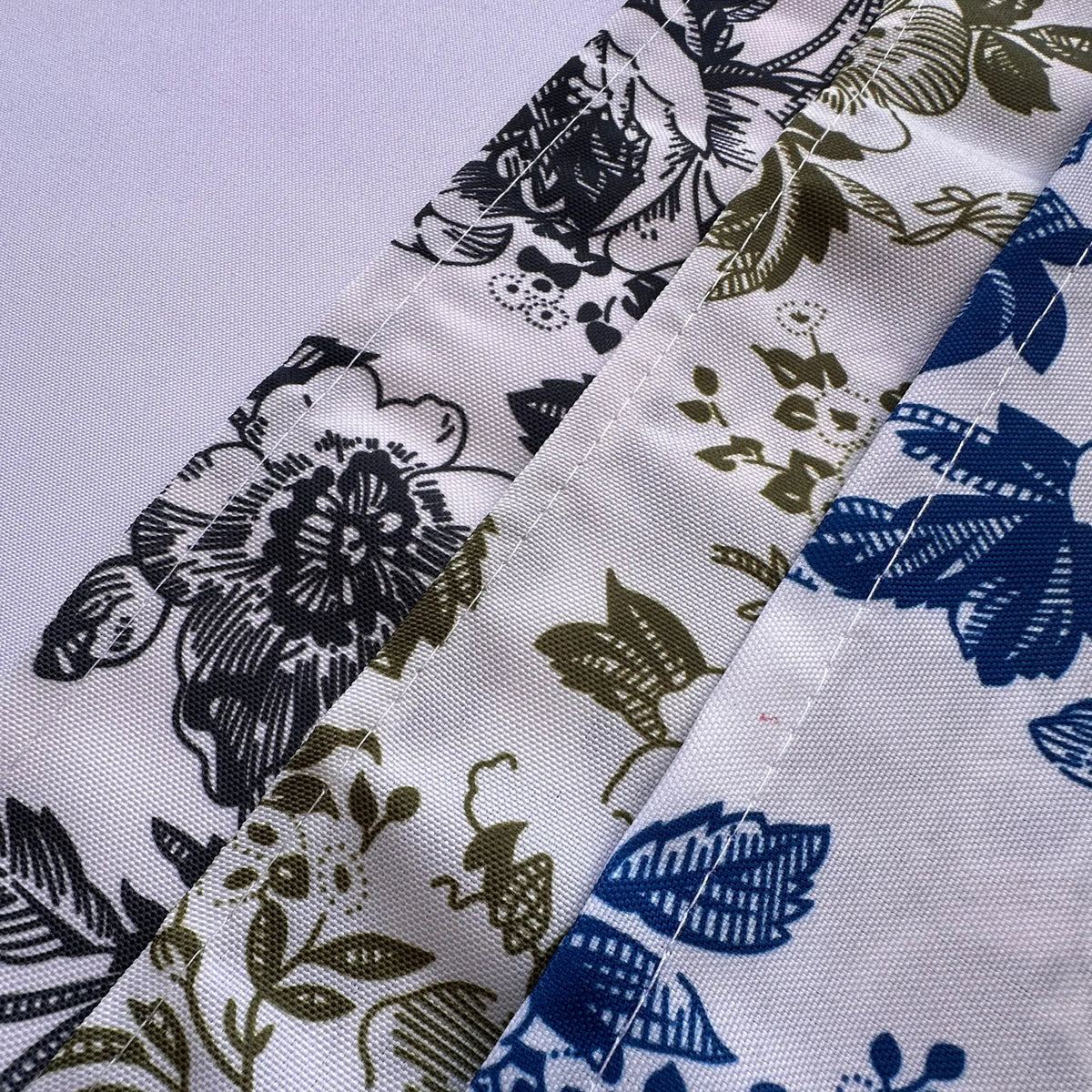 Close-up of a white fabric with two floral printed borders, one in black and white and the other in blue and white, separated by a stitched seam.