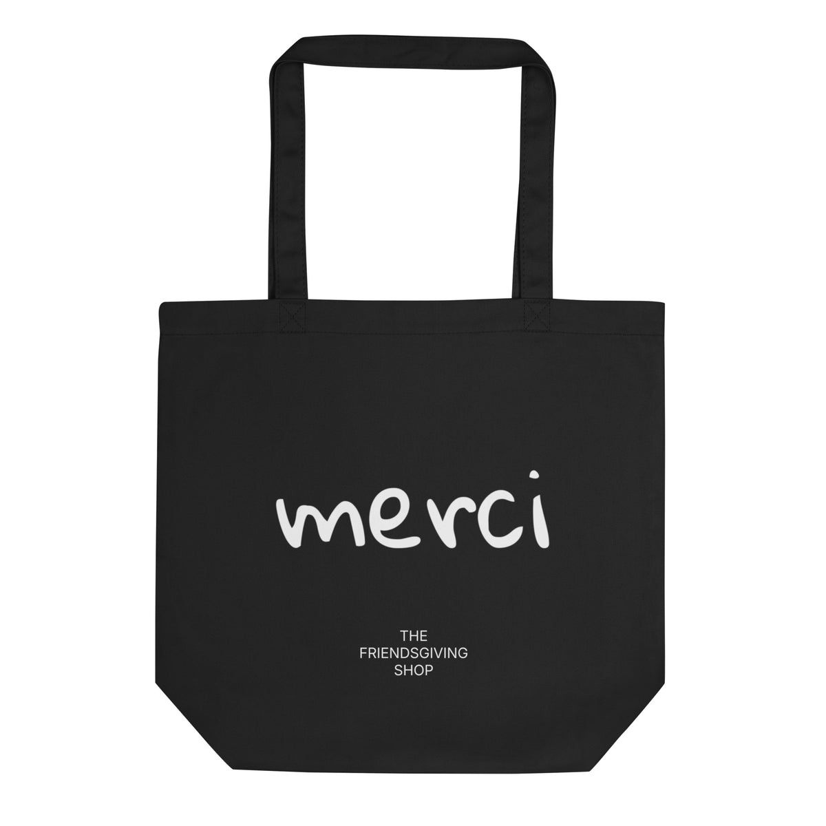 Black tote back with text "merci" in white font and underneath text "The Friendsgiving Shop" in white 