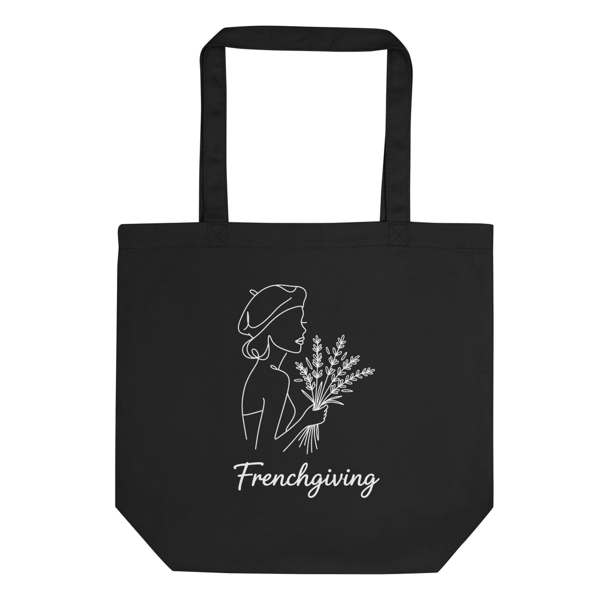 A black canvas tote bag with black handles, featuring a white line art graphic of a woman in a beret holding a bouquet of lavender, with the word 'Frenchgiving' printed below.