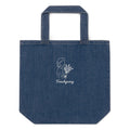 A blue denim tote bag with a white line-art graphic of a woman holding flowers and the text 'Frenchgiving' printed on the front, set against a plain white background.