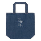 A blue denim tote bag with a white line-art graphic of a woman holding flowers and the text 'Frenchgiving' printed on the front, set against a plain white background.