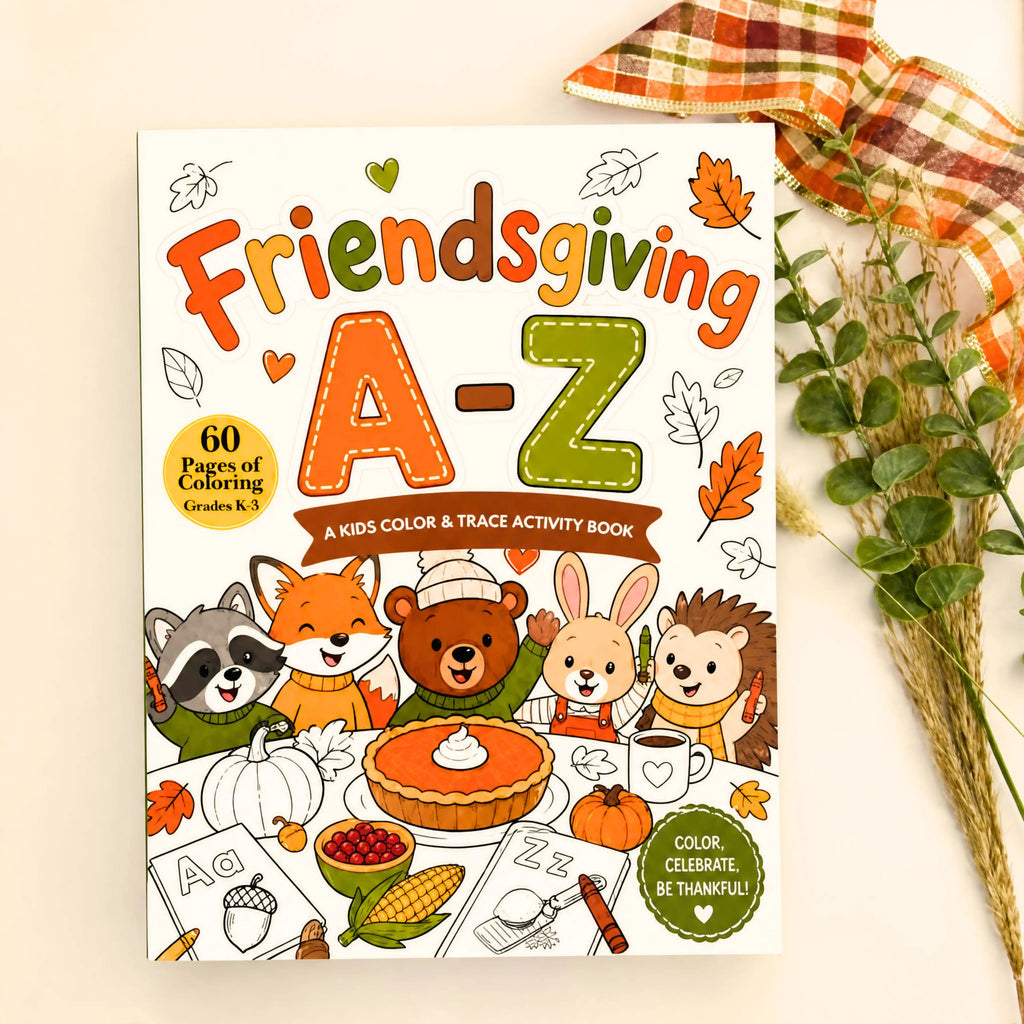 Friendsgiving A-Z Kids Color & Trace Activity Book cover displayed on a light gray surface with a plaid ribbon and dried grasses as styling props.