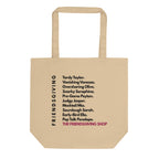 A beige canvas tote bag with printed black text listing friendship tropes and the phrase 'THE FRIENDSGIVING SHOP' in pink, shown on a plain white background.