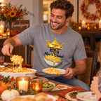 Man scooping mac n cheese wearing a grey t-shirt with a King crown and text "King of Mac 'n Cheese" with a bowl of mac n cheese on it Friendsgiving gathering table
