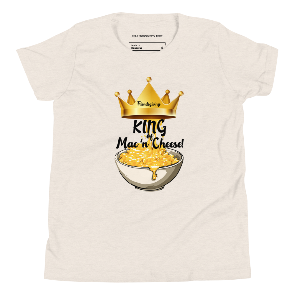 An off-white crewneck t-shirt featuring a graphic print of a golden crown, a bowl of mac and cheese, and the text 'Friendsgiving King of Mac 'n' Cheese!'. The inner collar shows the brand 'The Friendsgiving Shop'.