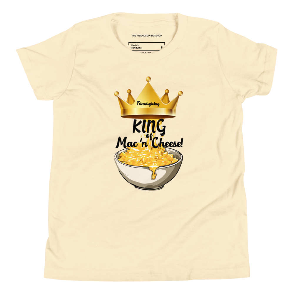 A natural colored short-sleeve t-shirt with a graphic print of a golden crown, the word 'Friendsgiving', and a bowl of macaroni cheese with the text 'King of Mac 'n' Cheese!'. The inner collar label shows the brand 'The Friendsgiving Shop'.