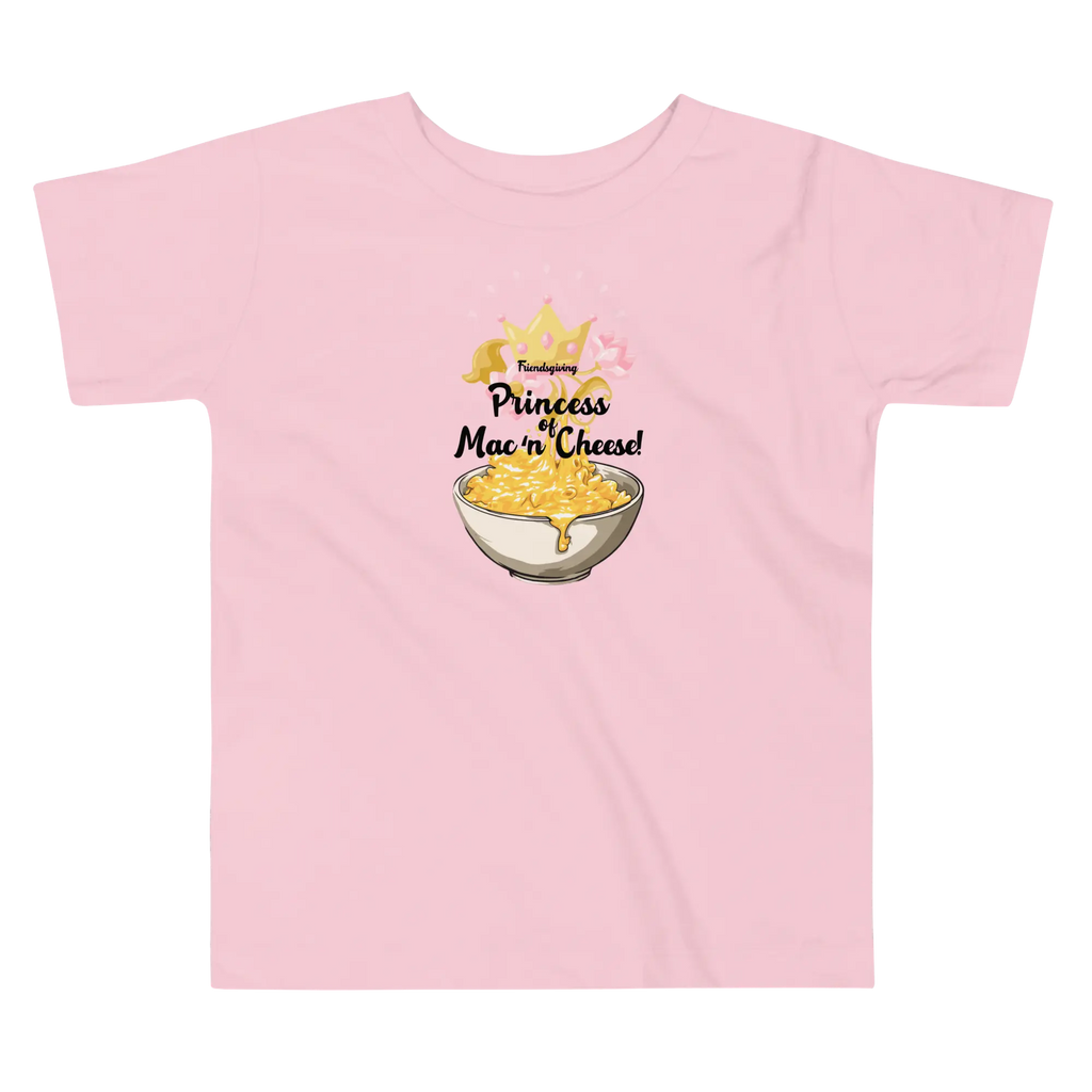 A light pink short-sleeve t-shirt with a graphic on the chest that reads 'Friendsgiving Princess of Mac 'n' Cheese!' above an illustration of a bowl of macaroni and cheese with a gold crown.