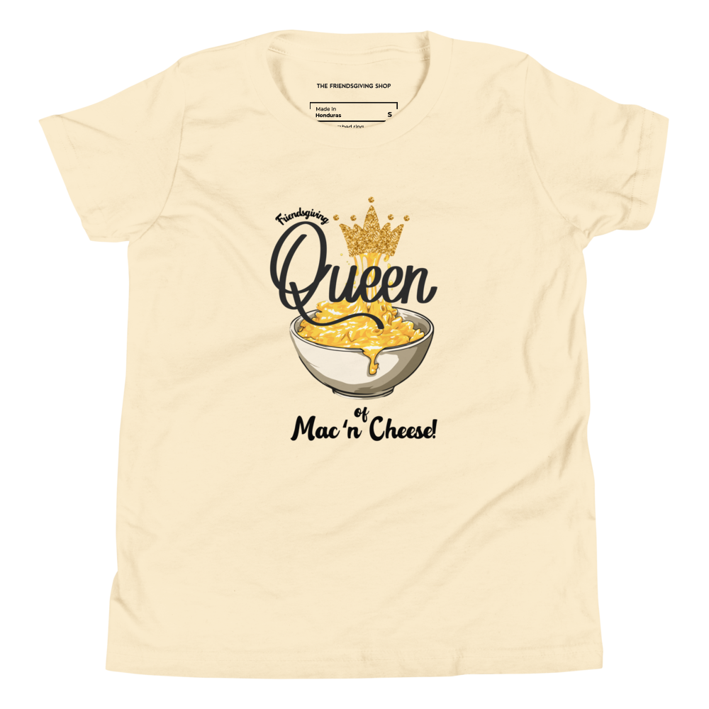 A light yellow-colored short-sleeve t-shirt with a graphic print of a bowl of mac and cheese topped with a gold crown, accompanied by the text 'Queen of Mac 'n Cheese!'. The inner collar label shows the brand 'The Friendsgiving Shop'.