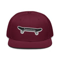A maroon flat-brim snapback cap featuring an embroidered black skateboard with white wheels and the text 'Friendsgiving' on the front.