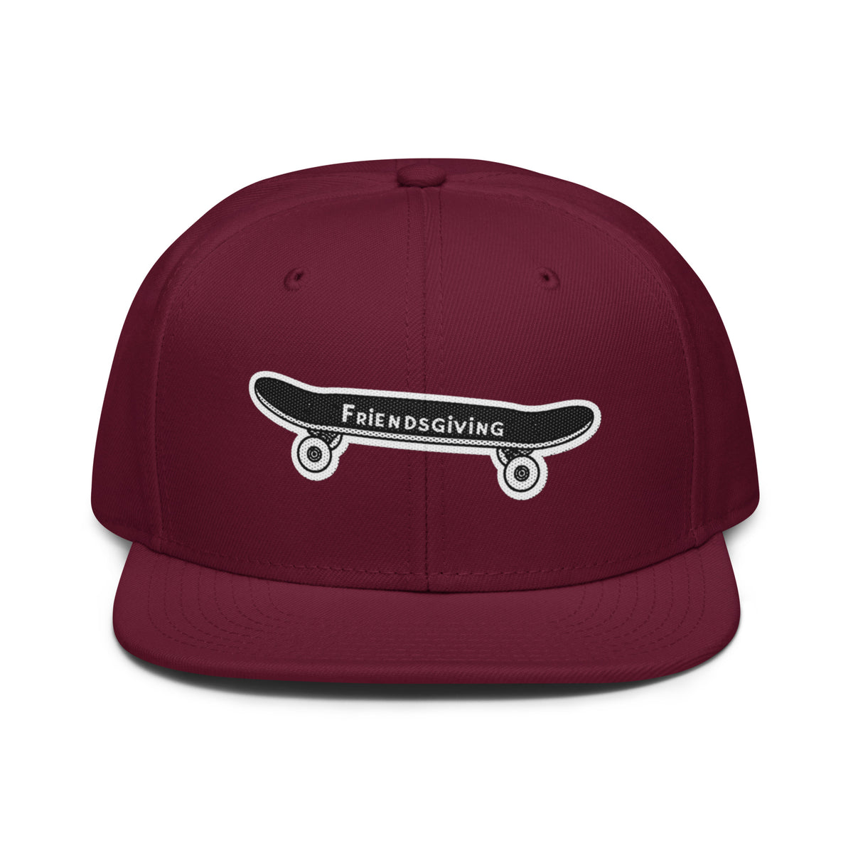 A maroon flat-brim snapback cap featuring an embroidered black skateboard with white wheels and the text 'Friendsgiving' on the front.