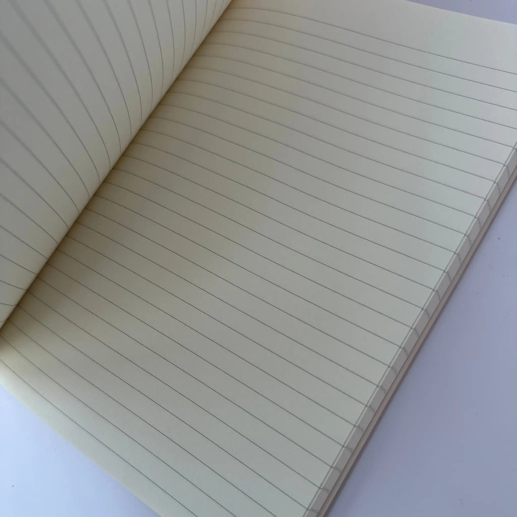 An open notebook with cream-colored, lined pages showing fine horizontal ruling on a light background.
