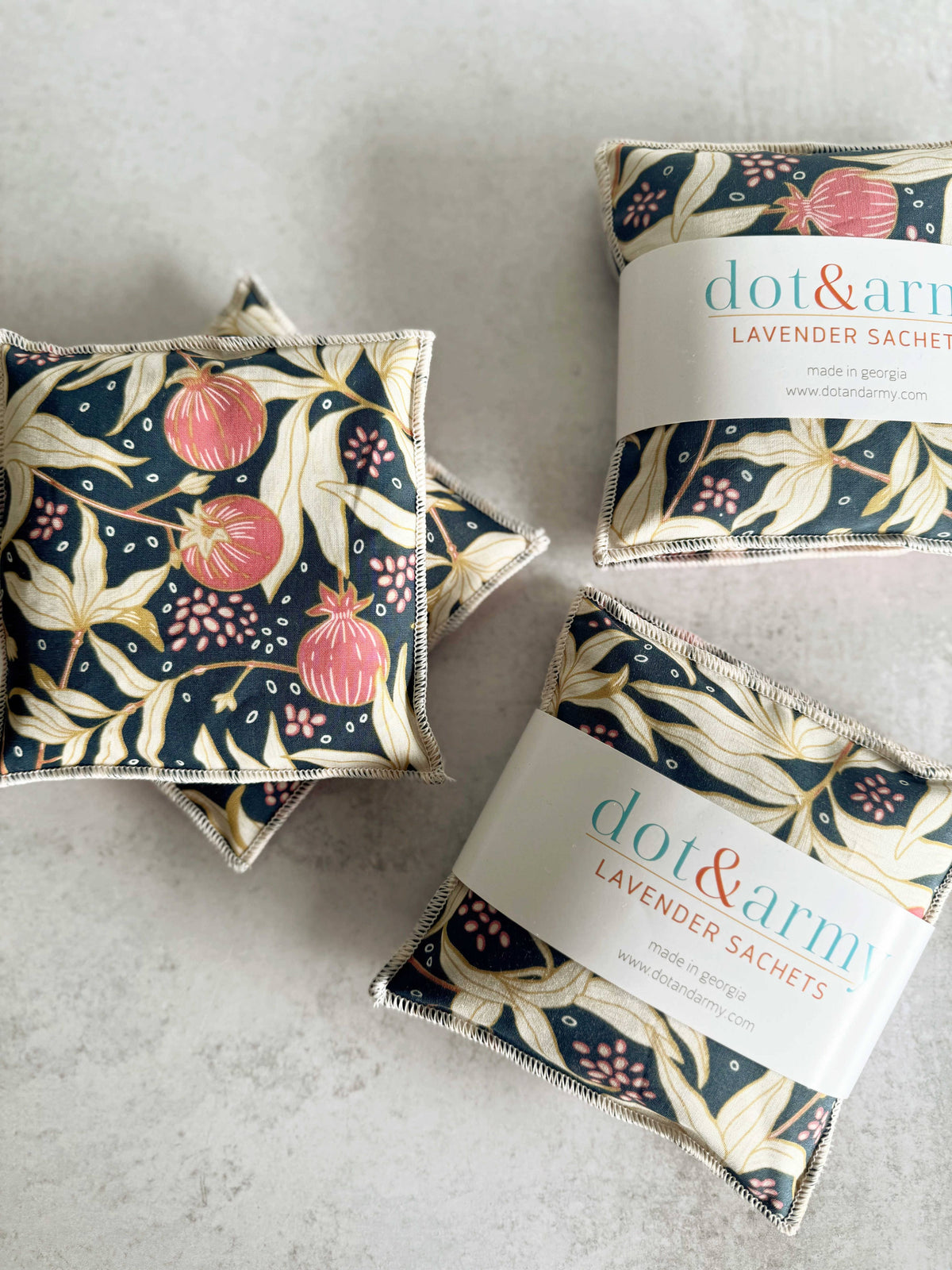 Three floral-patterned lavender sachets with 'dot & arum' labels on a light gray surface.