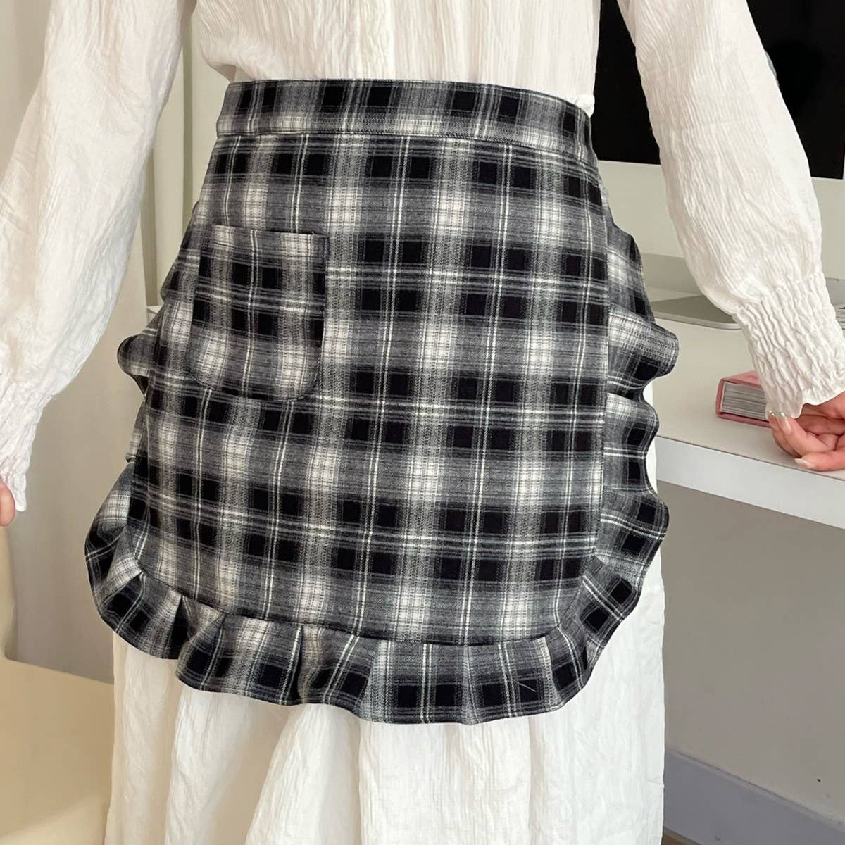 Person wearing a black and white plaid skirt with a blurred background