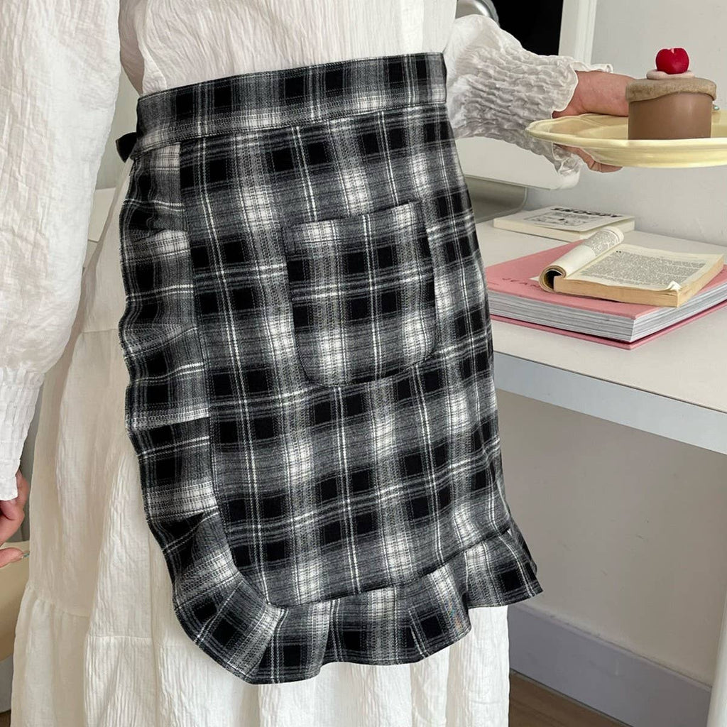 Person wearing a black and white plaid apron in an indoor setting.