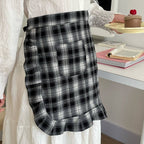 Person wearing a black and white plaid apron in an indoor setting.