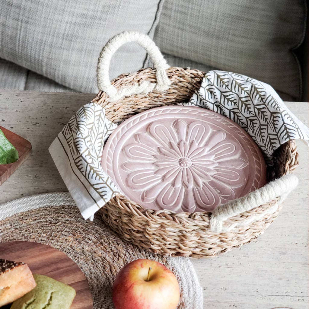 Pink decorative item in a woven basket on a wooden surface with an apple and bread slices.