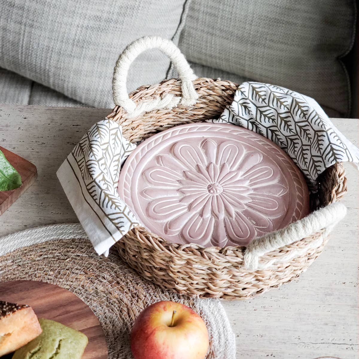 Pink decorative item in a woven basket on a wooden surface with an apple and bread slices.