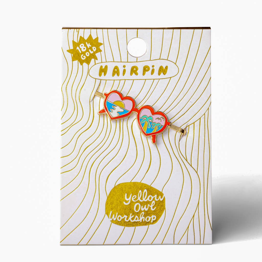 A 18K gold-plated heart-shaped hair pin by Yellow Owl Workshop, shown on its white and gold patterned retail backing card.