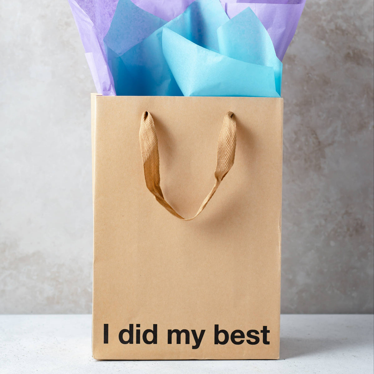 Gift bag with 'I did my best' text and colorful tissue paper on a neutral background