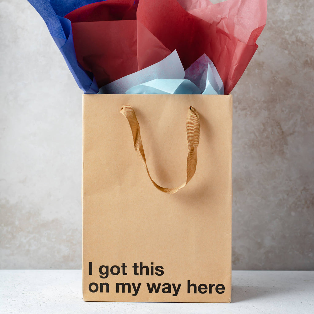 Brown gift bag with colorful tissue paper and motivational text on a neutral background
