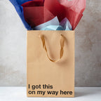Brown gift bag with colorful tissue paper and motivational text on a neutral background