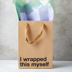 Brown gift bag with text 'I wrapped this myself' and colorful tissue paper on a neutral background