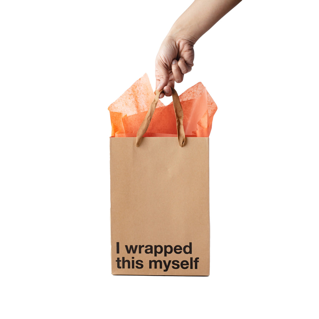 Brown paper bag with 'I wrapped this myself' text, held by a hand with orange tissue paper.