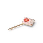 A gold-tone hair clip shaped like a book with a light pink cover, featuring a red oval logo with the word 'joy' and the phrase 'the joy of cooking' in gold lettering.