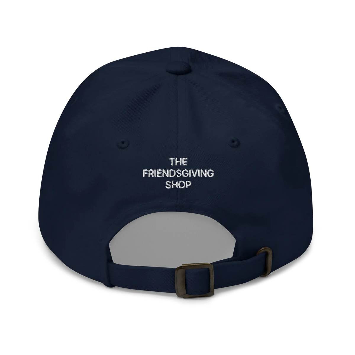 A navy blue baseball cap shown from the back, featuring the white embroidered text 'THE FRIENDSGIVING SHOP' on the back panel and an adjustable dark metal buckle strap.
