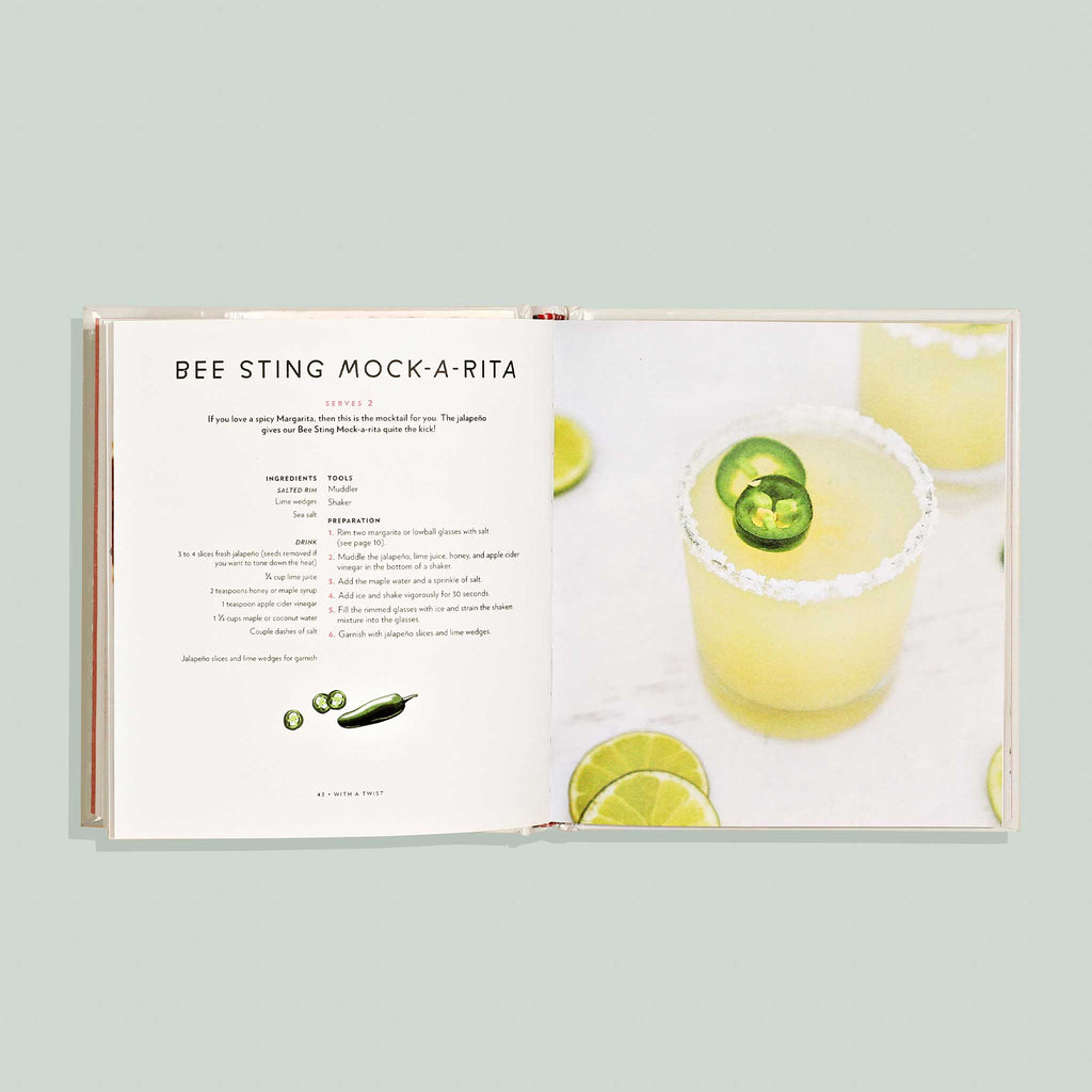 Open book showing a recipe for 'Bee Sting Mock-A-Rita' with a mocktail image on a light green background.