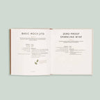 Open book displaying recipes for 'Basic Mock Jito' and 'Zero Proof Sparkling Wine' on a light green background.